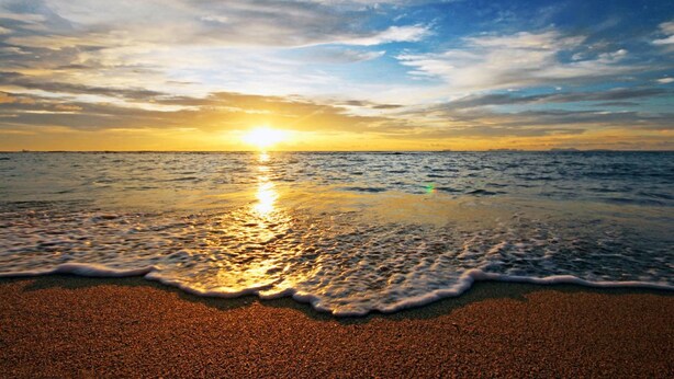 A beach with waves at sunset.