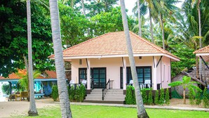 A building with a red-tiled roof, surrounded by palm trees and greenery.
