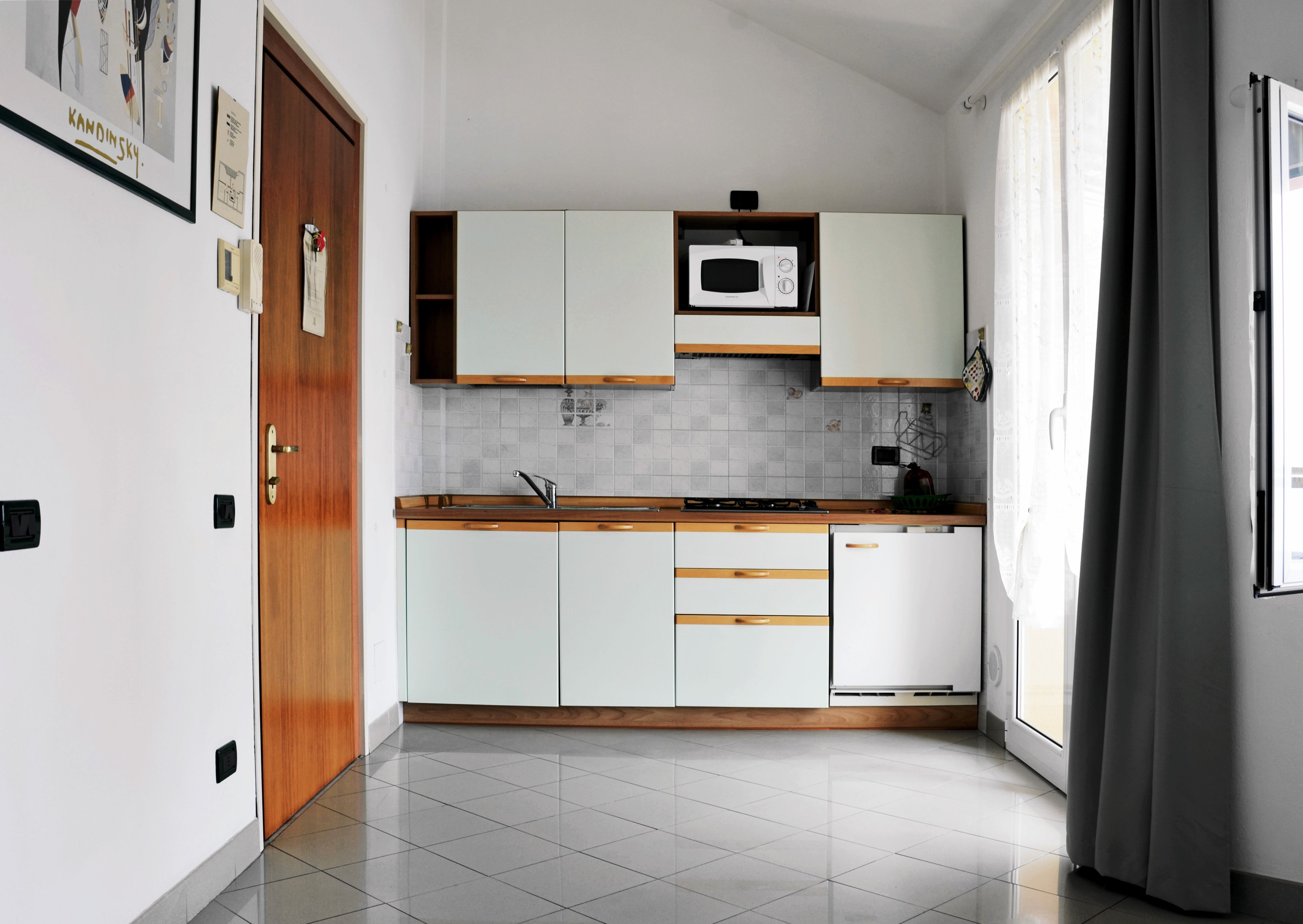 Une cuisine moderne avec des meubles blancs, un four à micro-ondes et un évier.