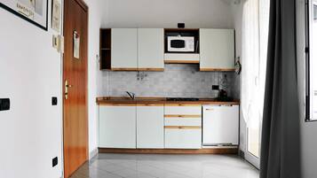 Une cuisine moderne avec des meubles blancs, un four à micro-ondes et un évier.