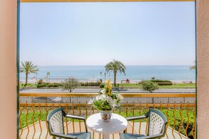 A balcony with a table and chairs, a potted plant, and a view of the sea and beach. - Residence Villa Alda (Pietra Ligure)
