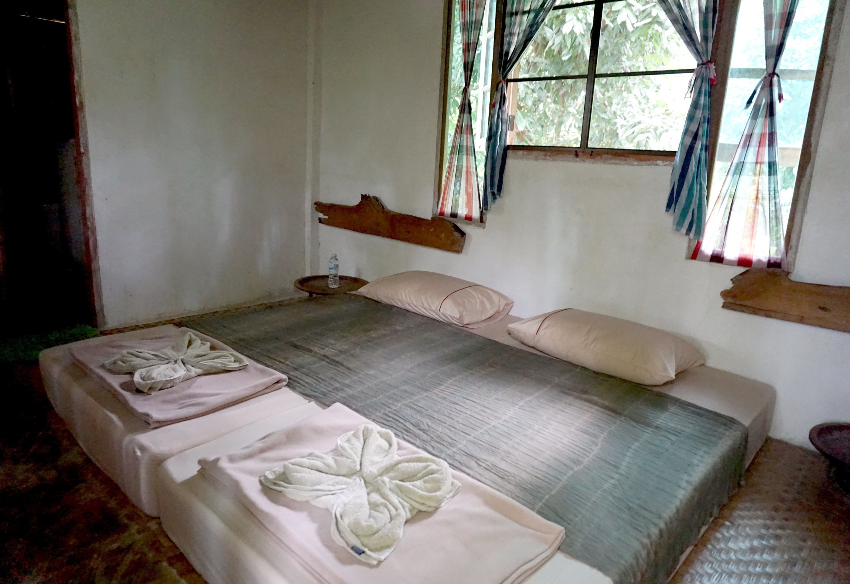 A room with a large bed, two bedside tables, and a window with curtains.