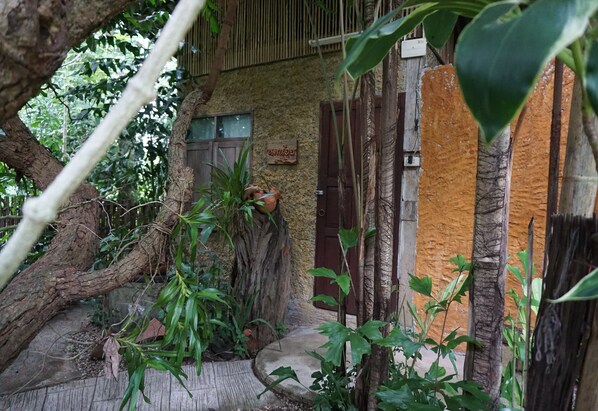 Un edificio rústico con una puerta de madera, un letrero y un árbol en primer plano.