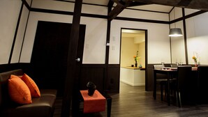 Une pièce avec un banc en bois foncé, une table avec des chaises et un luminaire suspendu.