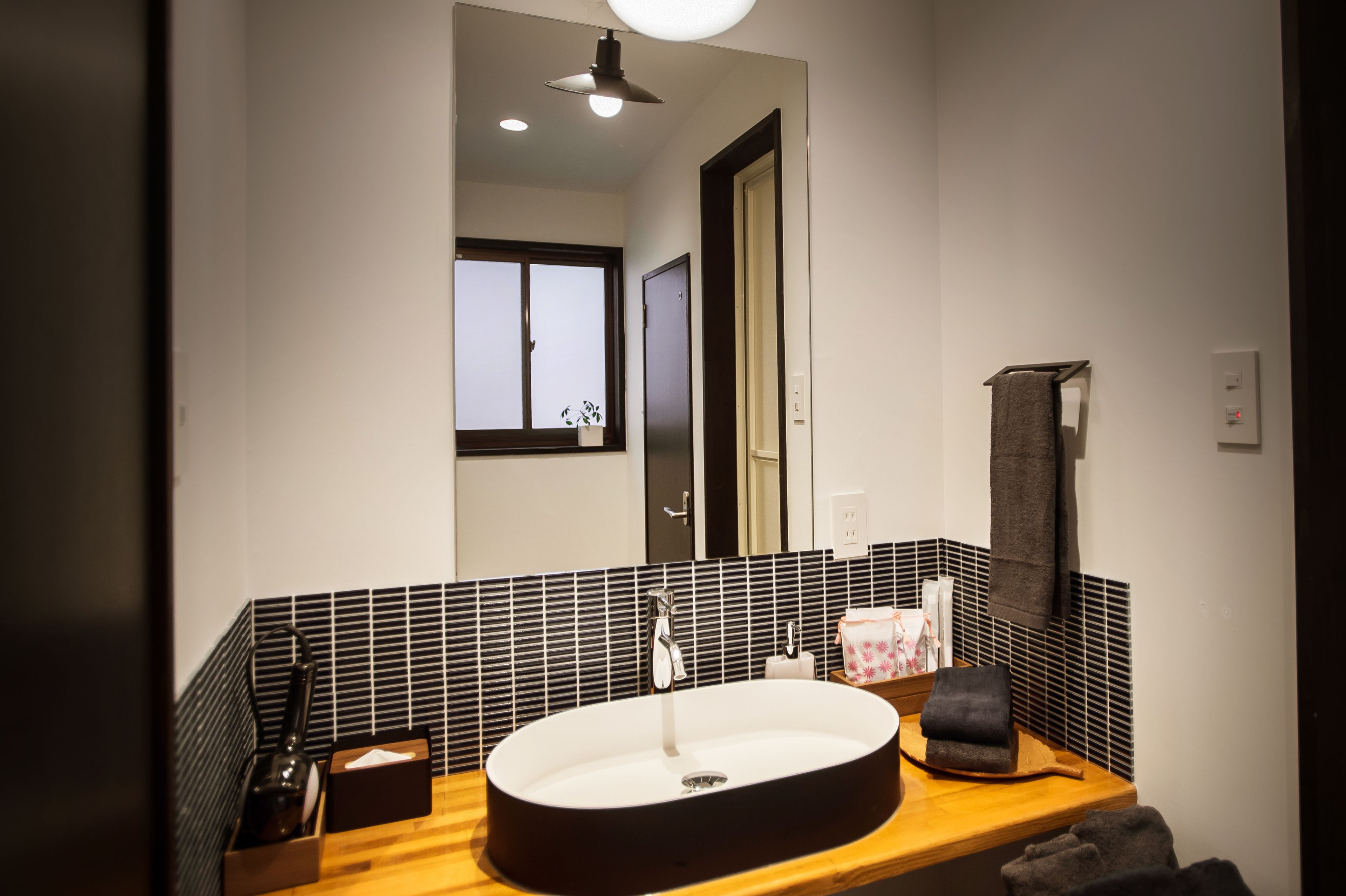 A modern bathroom with a large mirror, a round sink, and a wooden countertop.