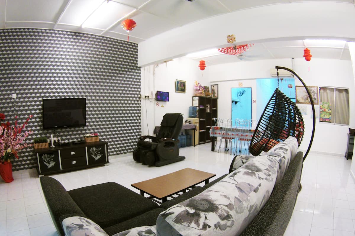 A living room with a sofa, a coffee table, a TV, and a patterned wall.