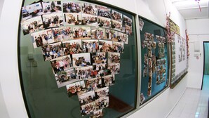 Un pasillo con una pared de vidrio curva que exhibe numerosas fotografías.