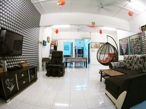 A modern living room with a flat-screen TV, a massage chair, a hanging chair, and a sofa. - 39 Guest House (Malacca City)