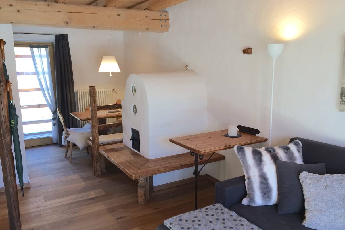 A cozy room with a wooden table, a sofa, and a fireplace.