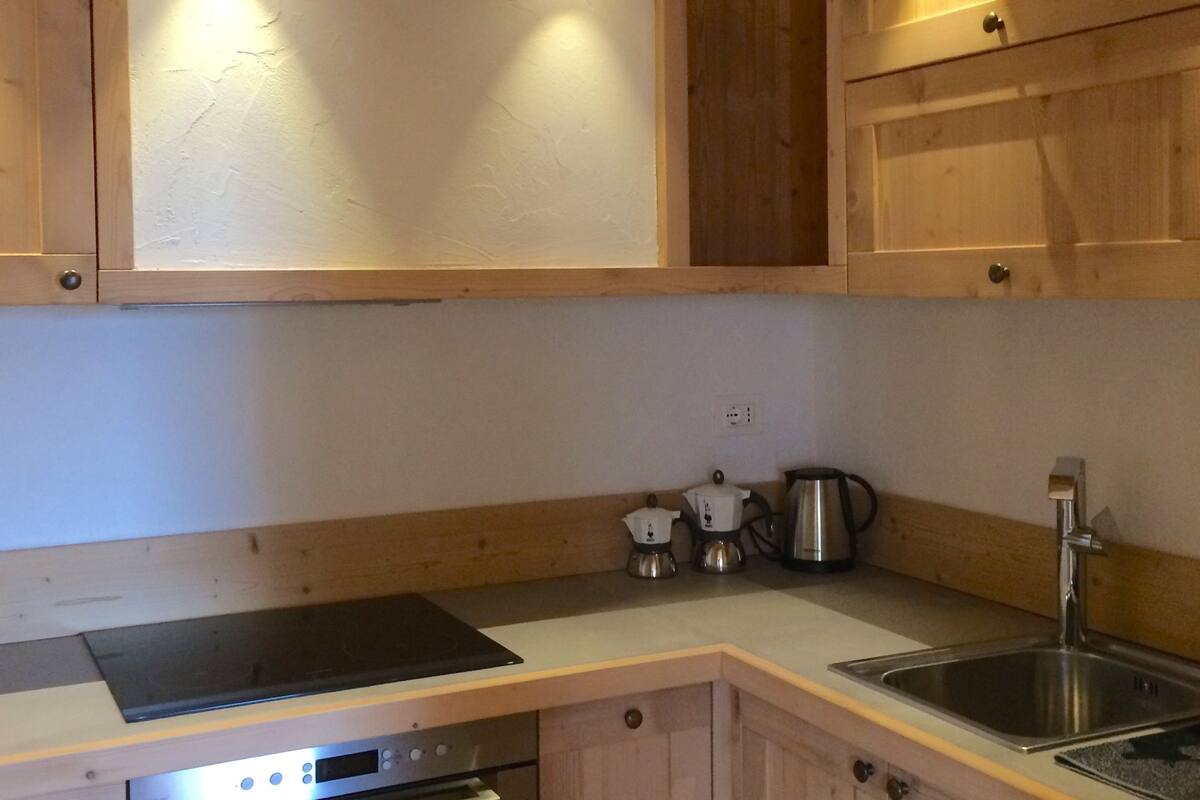 A kitchen with wooden cabinets, a stainless steel sink, a built-in oven, and a coffee maker.