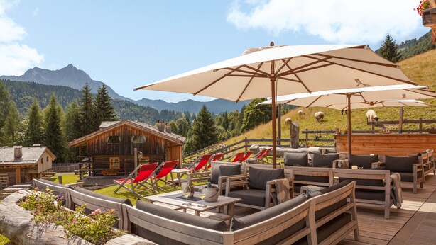 A wooden deck with outdoor seating, a wooden cabin, and a mountainous backdrop. - Chalet-Hôtel Borgo Eibn Mountain Lodge (Relais du Silence) (Sauris)