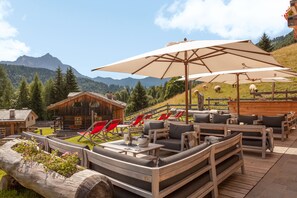 A wooden deck with outdoor seating, a wooden cabin, and a mountainous backdrop. - Chalet-Hôtel Borgo Eibn Mountain Lodge (Relais du Silence) (Sauris)
