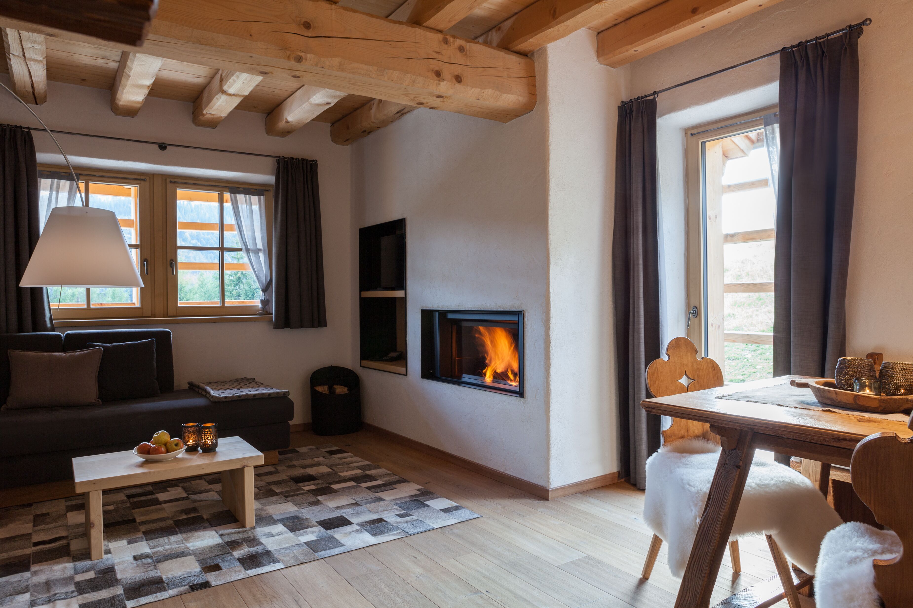 A cozy living room with a fireplace, a sofa, a dining table, and a checkered rug.