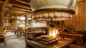 A rustic wooden interior with a large, round, stone oven and a grill table. - Chalet-Hôtel Borgo Eibn Mountain Lodge (Relais du Silence) (Sauris)