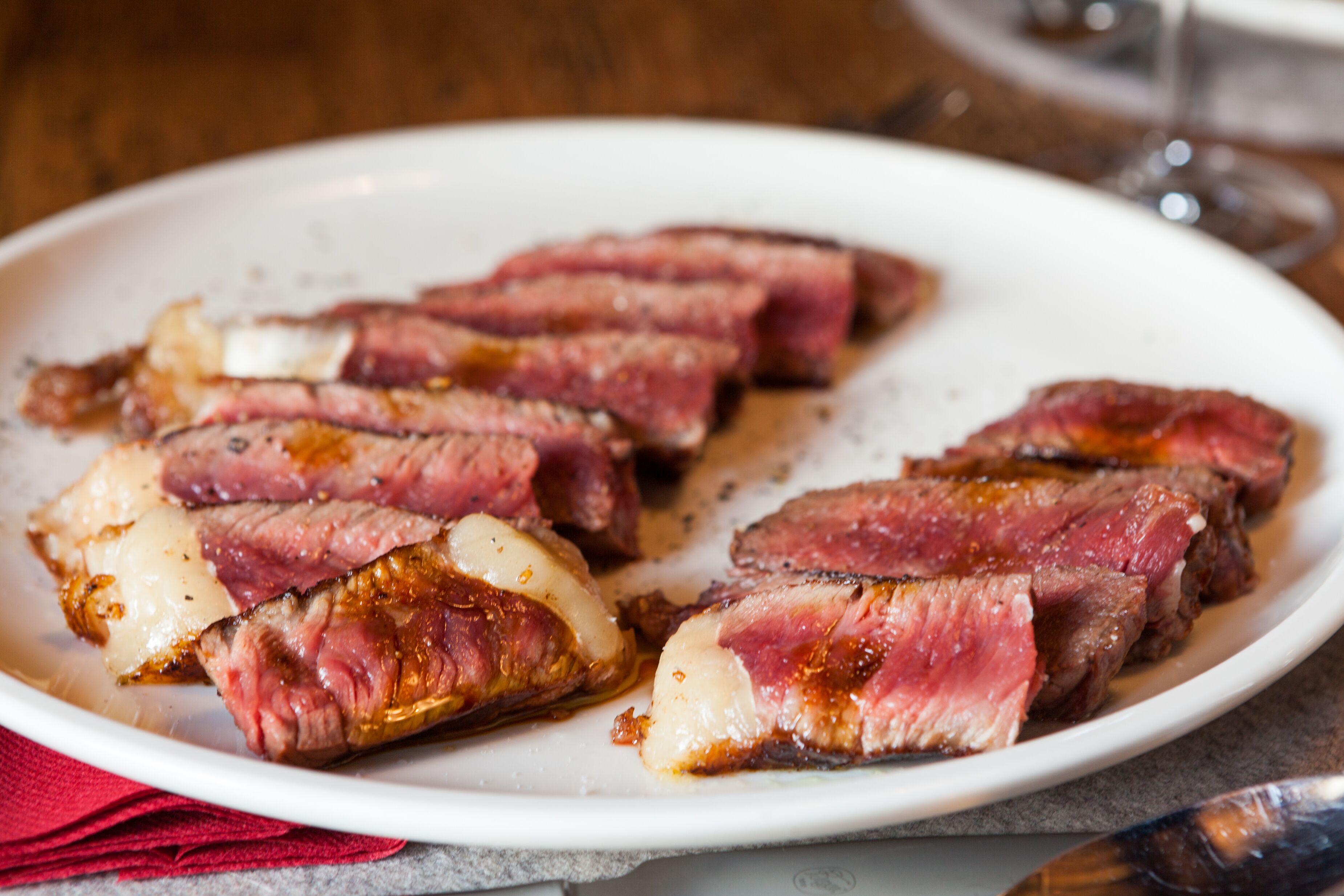 A plate of sliced steak with a white interior and a pink exterior, served on a white plate.