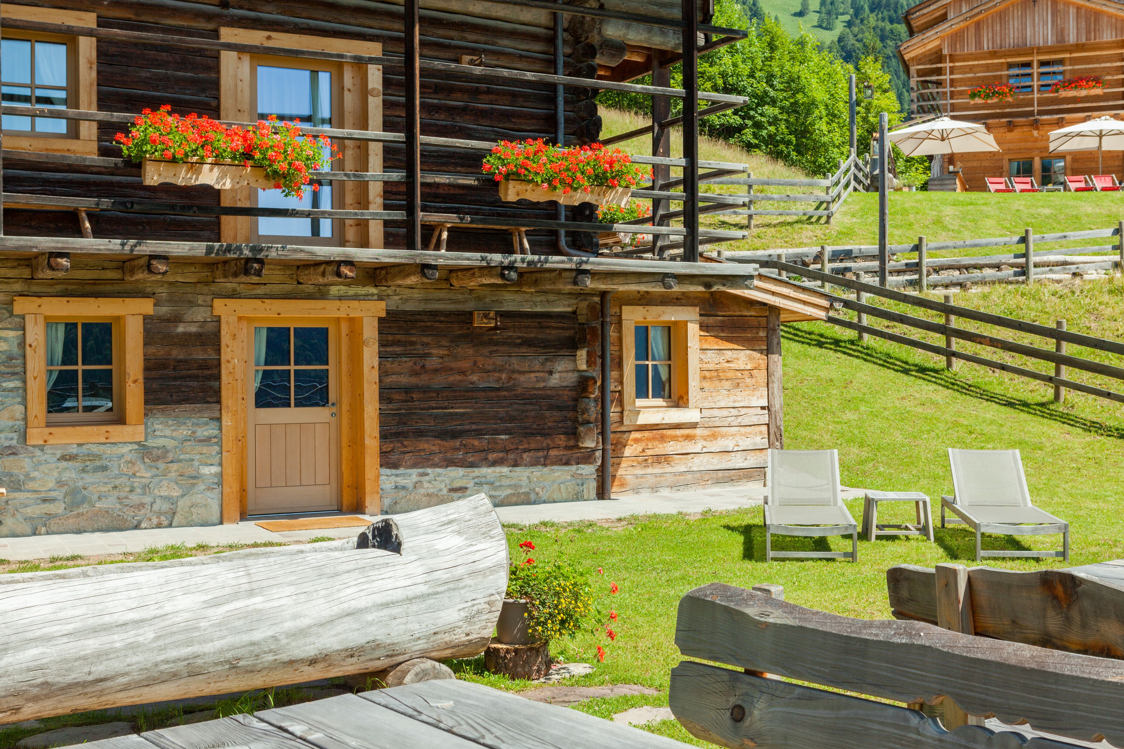 Una baita di legno con fondamenta in pietra, un pontile in legno e una recinzione in legno.
