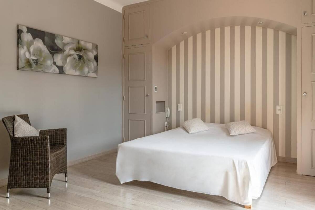 Een slaapkamer met een bed, een stoel, een deur en een gestreepte wand.