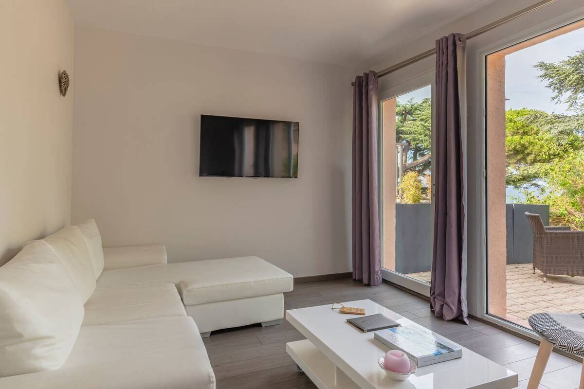 Een moderne woonkamer met een witte bank, een salontafel en een flatscreen televisie aan de muur.