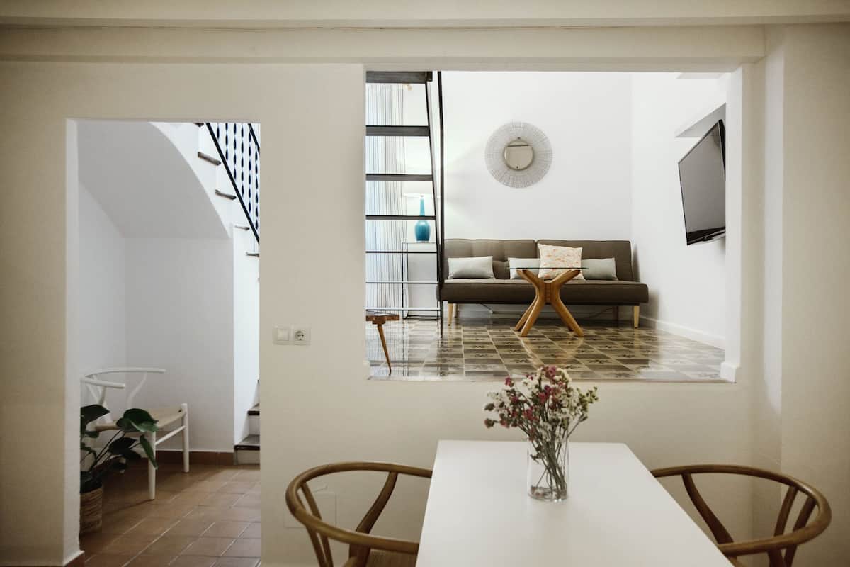 A modern living room with a sofa, a TV, and a dining area with a table and chairs.