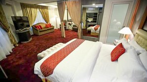 Una habitación de hotel con una cama grande, televisor, sofá y espejo.