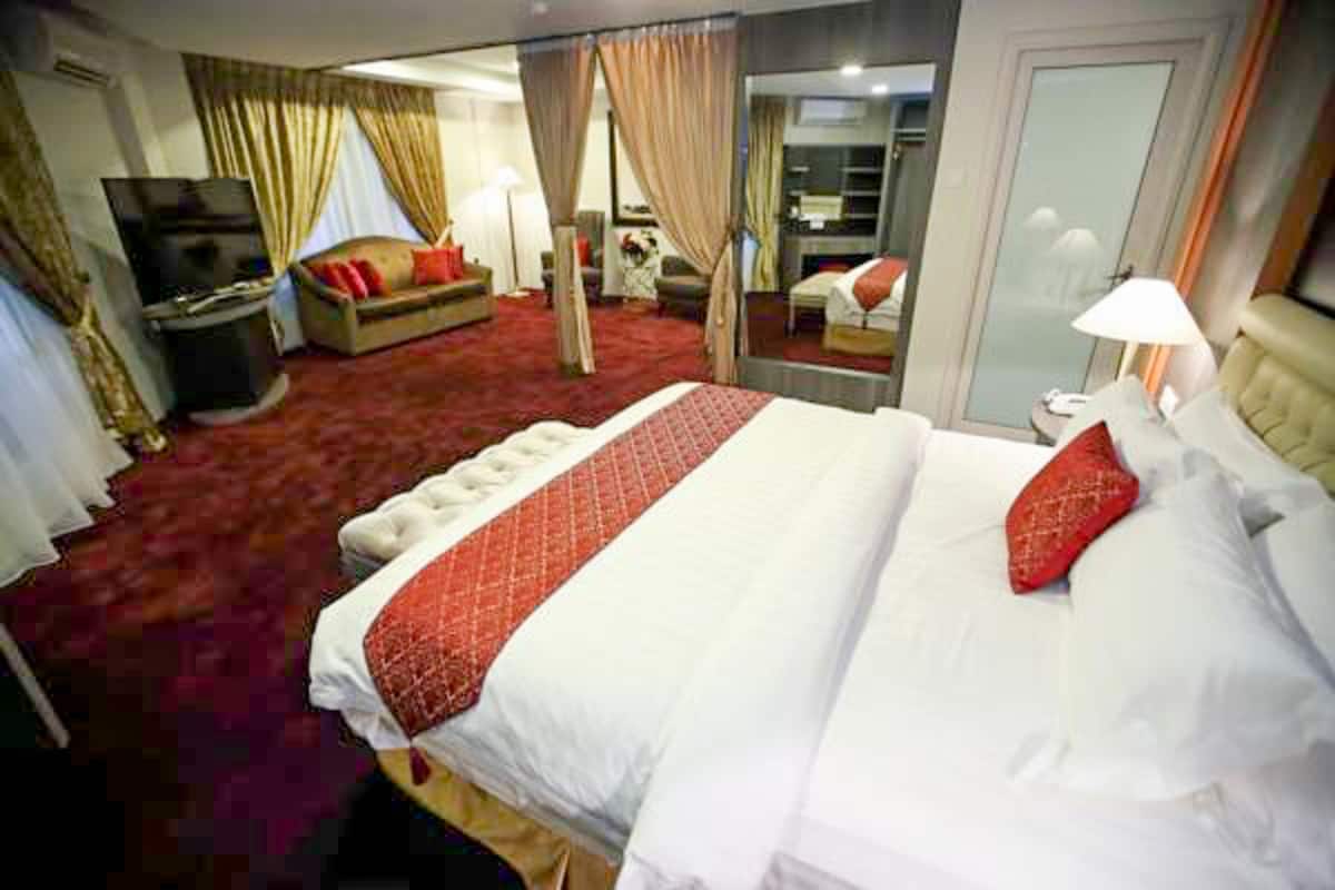 Une chambre d’hôtel avec un grand lit, une télévision, un canapé et un miroir.