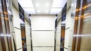 Vista del interior de un ascensor con paredes espejadas y un panel de luz central.