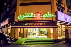 A hotel entrance with a sign in Arabic, a visible staircase, and a car parked in front. - Al Khatiri Hotel (Kota Bharu)