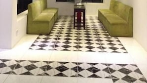 A modern living room with two green sofas, a patterned floor, and a large window. - Trang An Hotel (Hoa Lu)