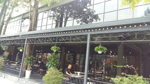 A restaurant with outdoor seating, large windows, and hanging plants. - Trang An Hotel (Hoa Lu)