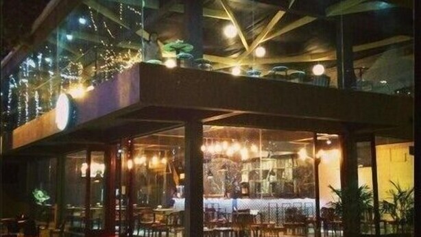 A modern building with a glass facade, outdoor seating area, and visible interior lighting. - Trang An Hotel (Hoa Lu)