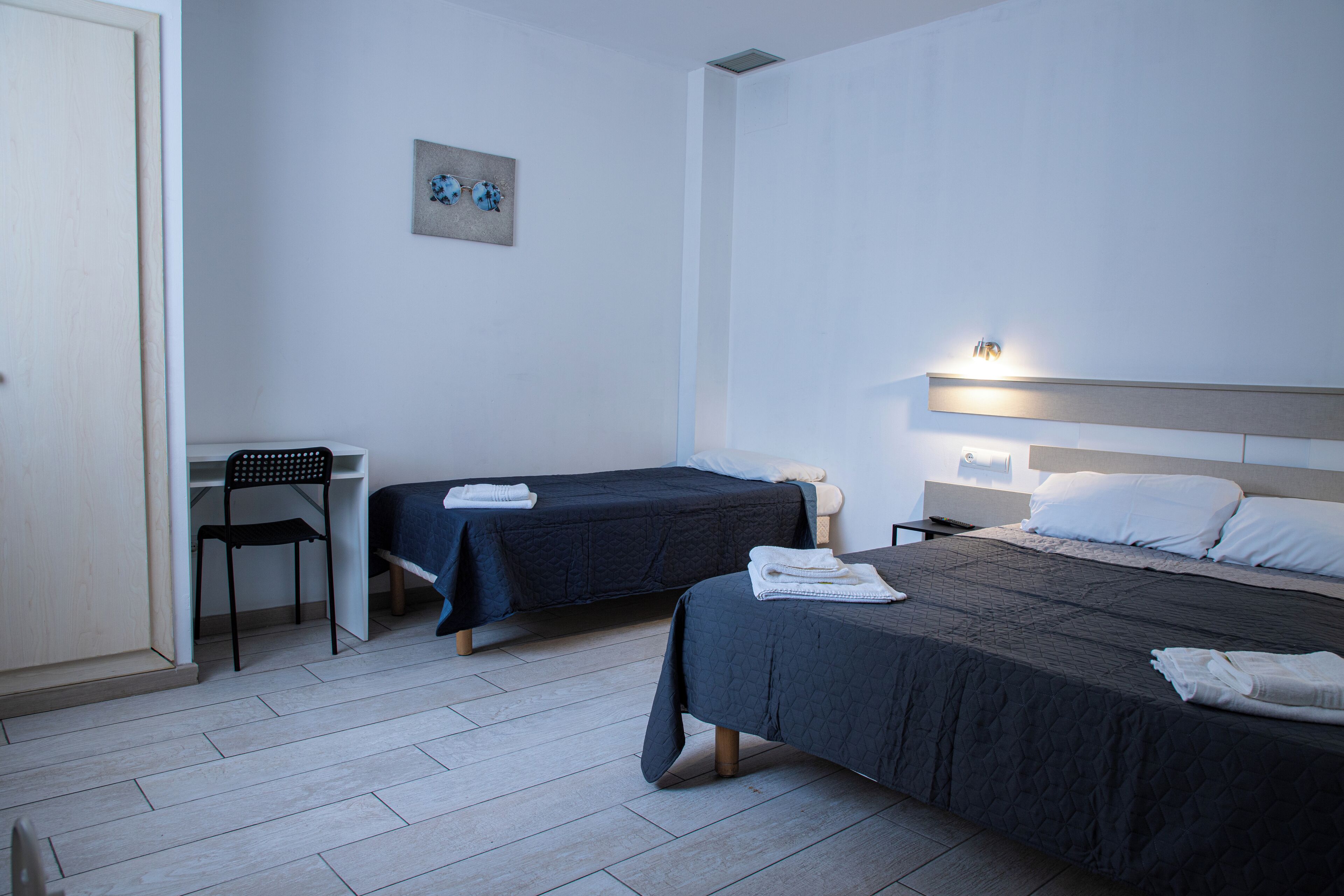 A hotel room with two beds, a desk, and a chair.