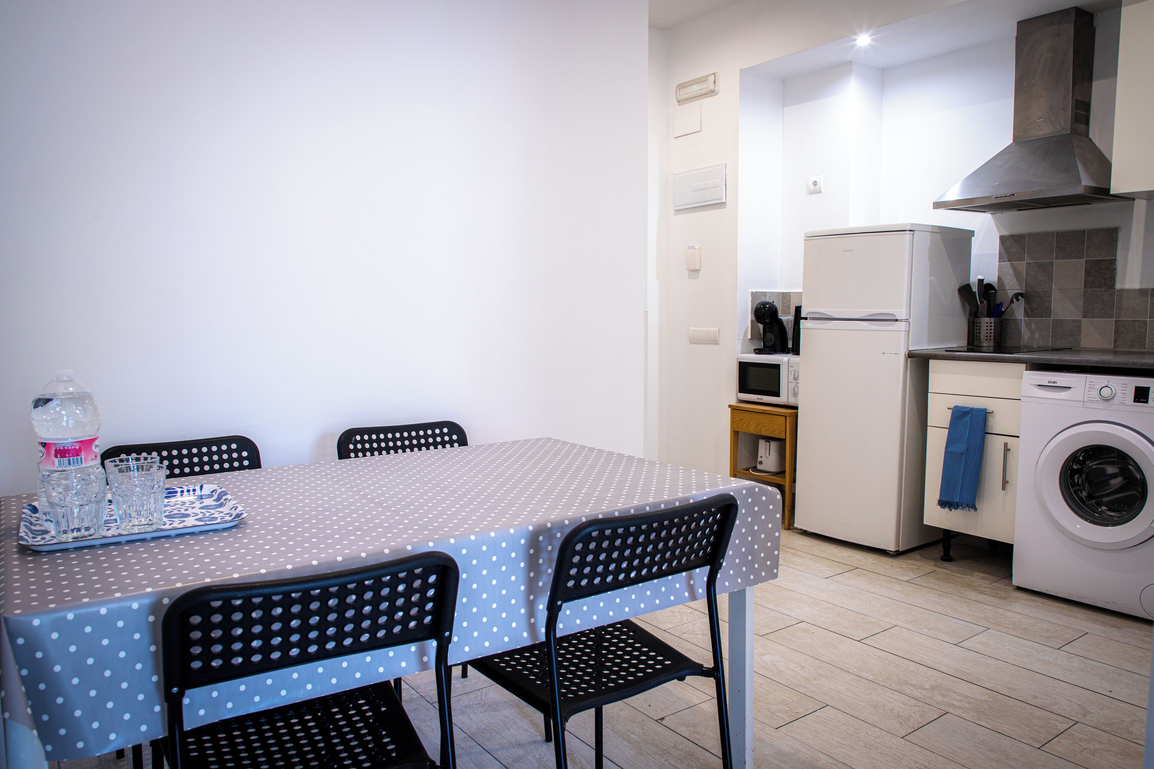 Una cocina compacta con una mesa de comedor, sillas, lavadora y refrigerador.