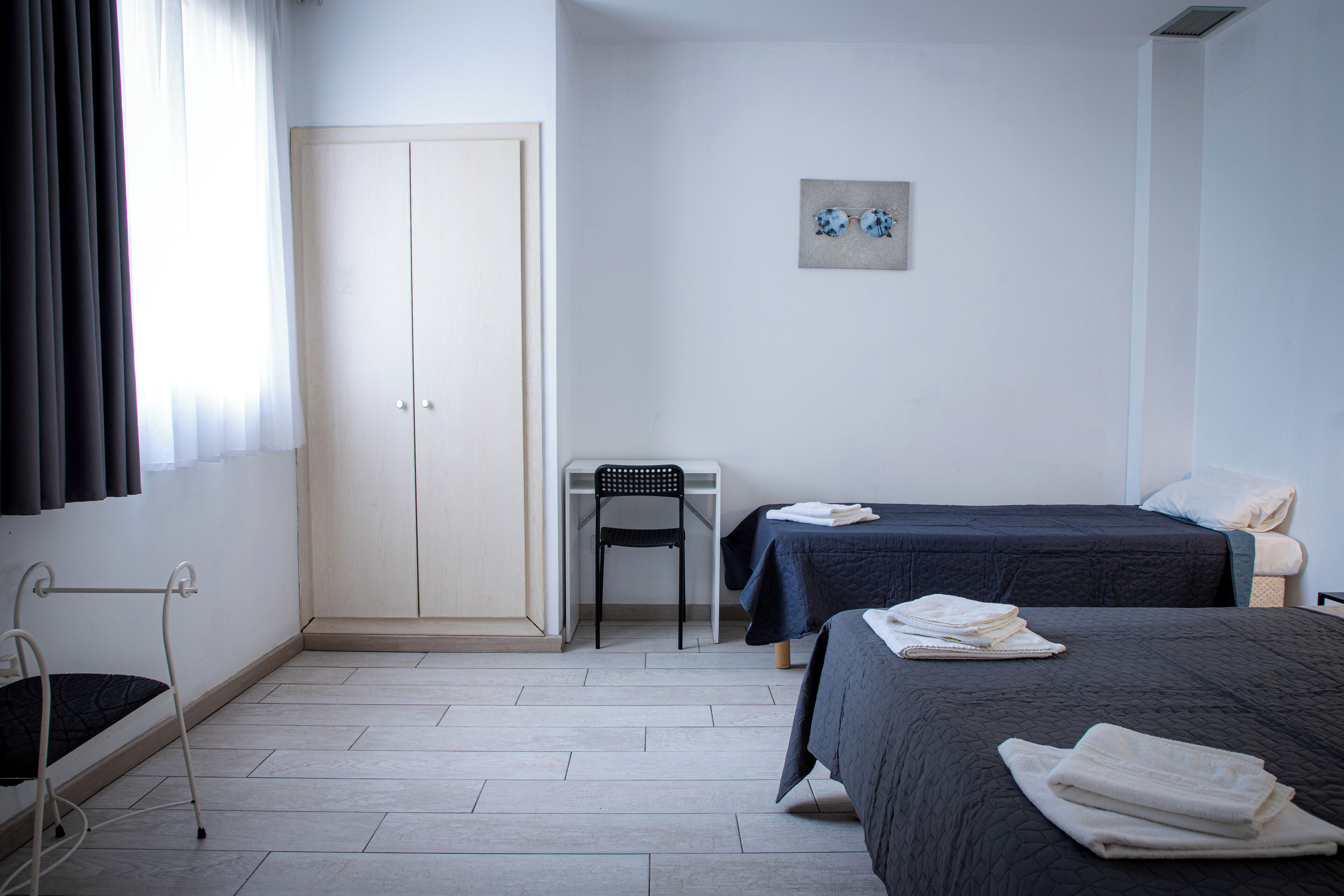 Ein Schlafzimmer mit zwei Betten, einem Schreibtisch, einem Stuhl und einem Kleiderschrank.