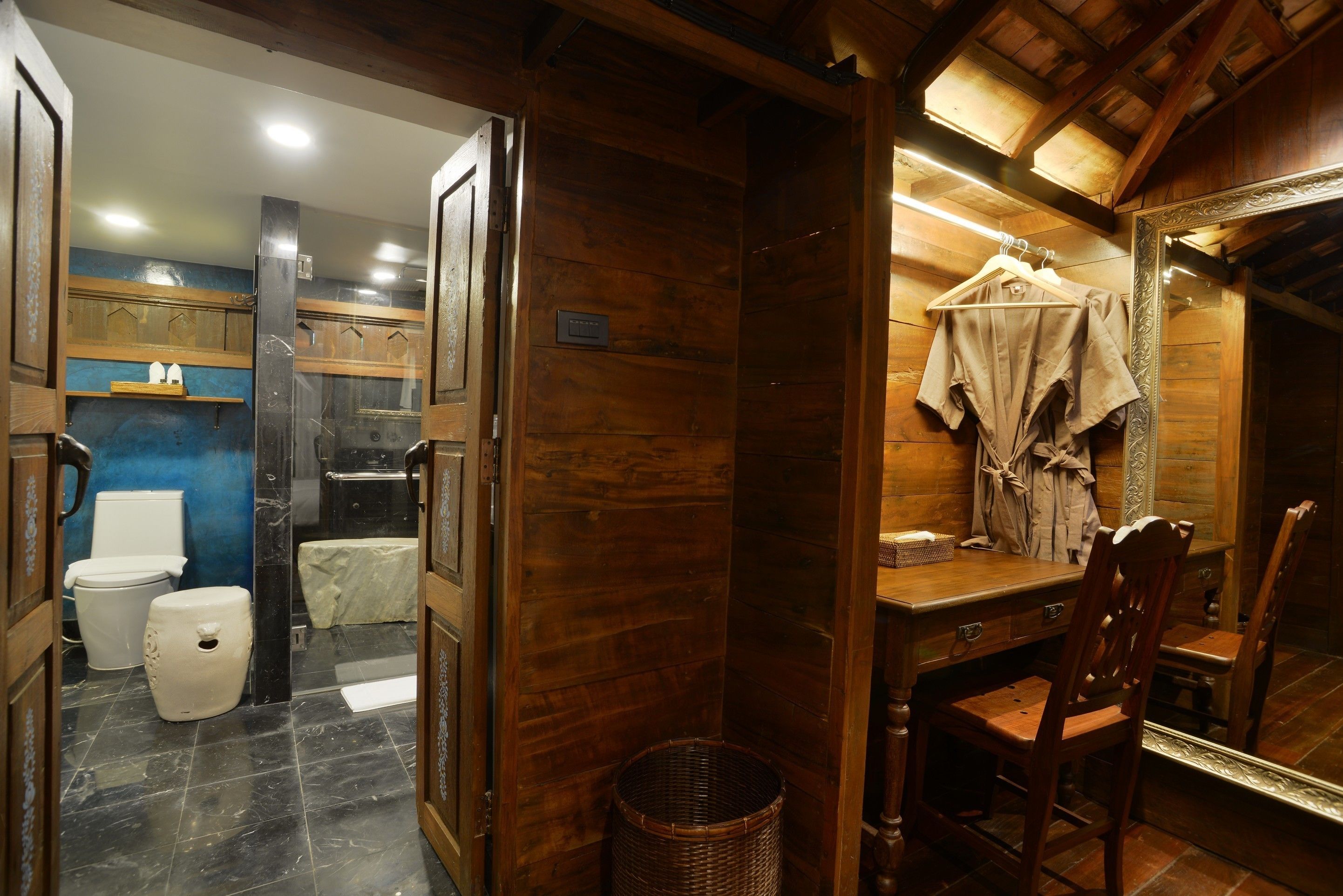 A wooden bathroom with a toilet, sink, and mirror.