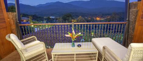 A balcony with wicker furniture, a table, and a vase of flowers.