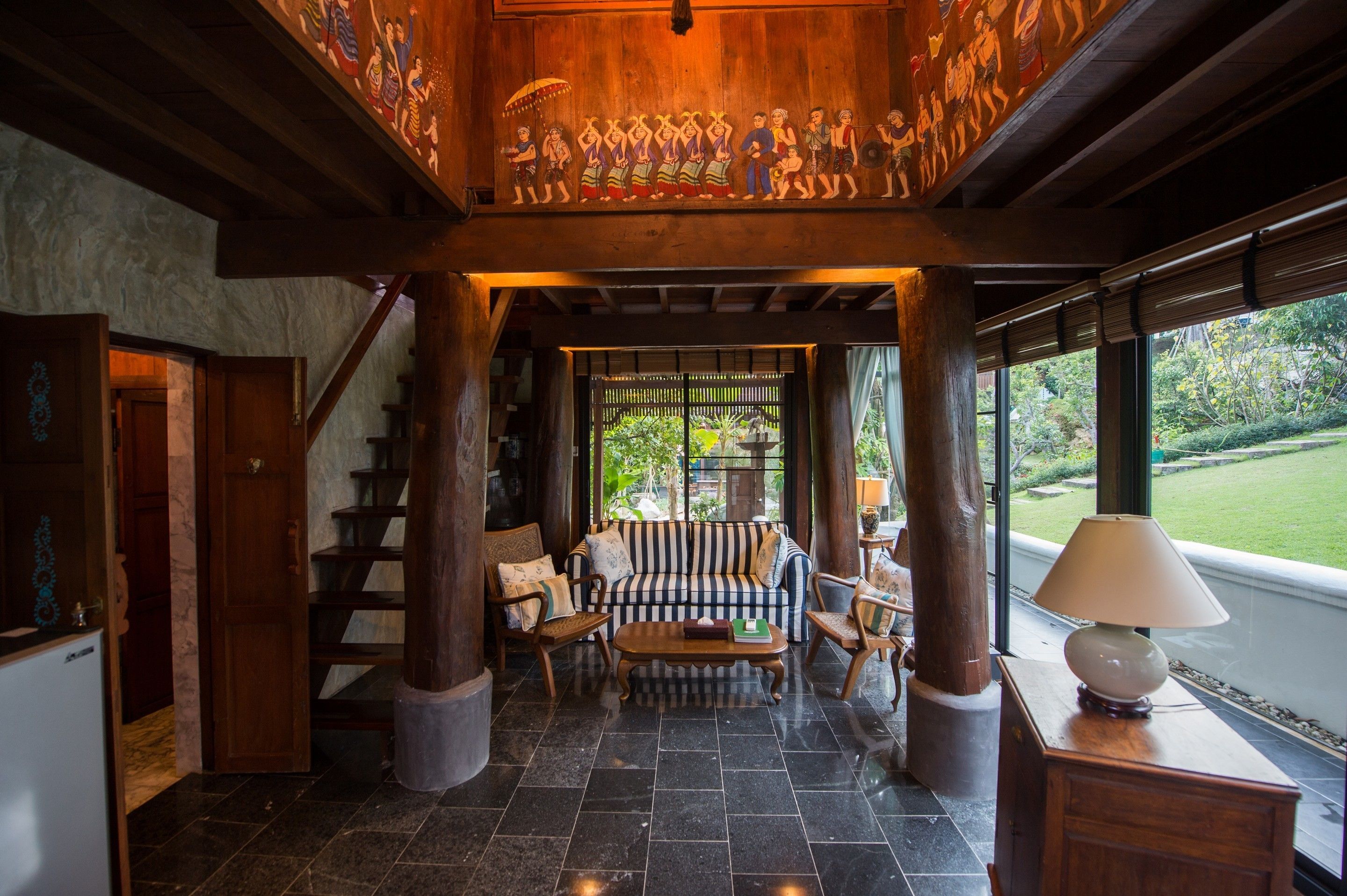 A spacious lobby with a high ceiling, a staircase, a sofa set, and a large window offering a view of the outdoors.