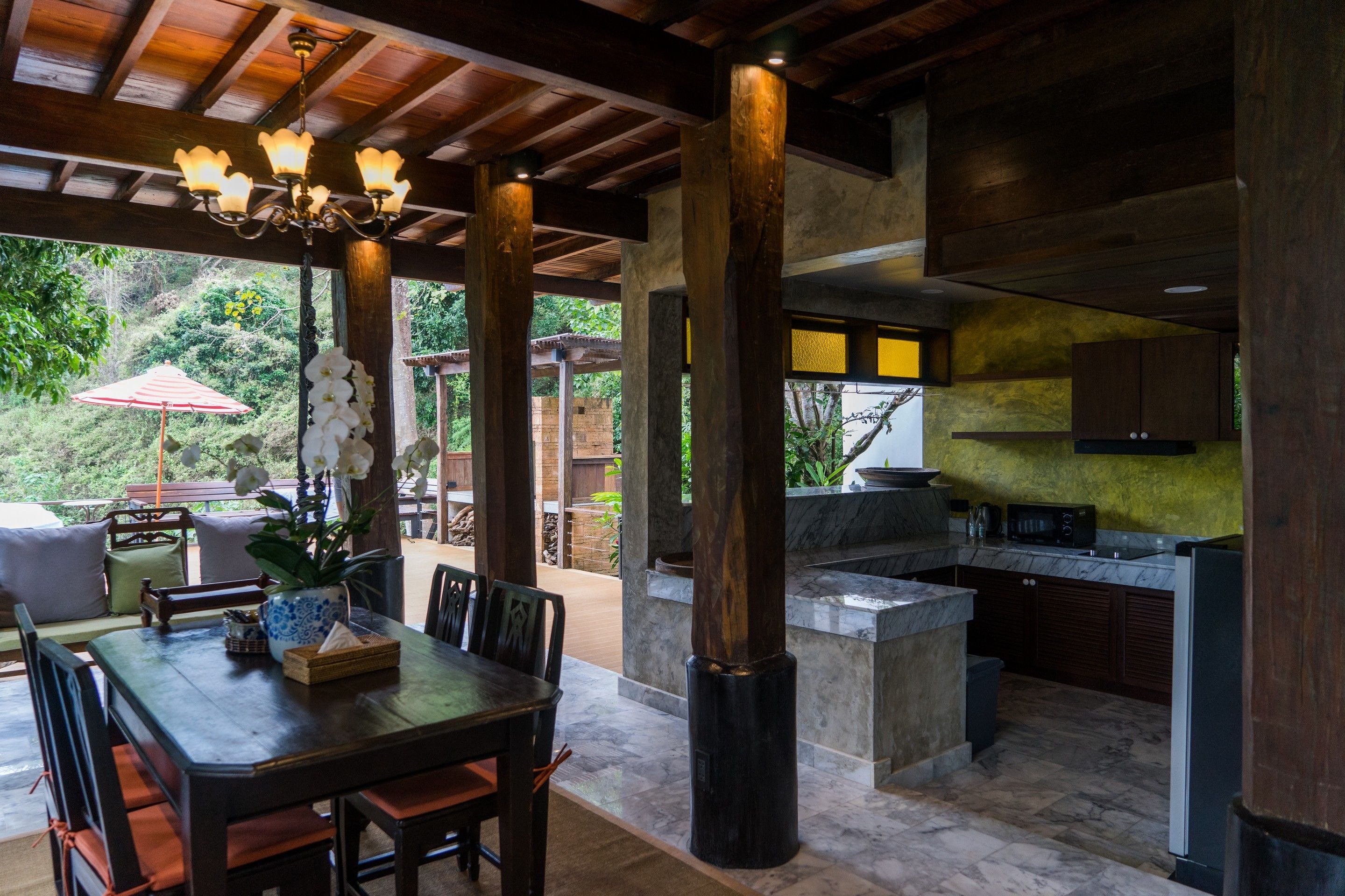 Una cocina amplia con una isla de piedra, vigas de madera y un comedor con mesa y sillas.