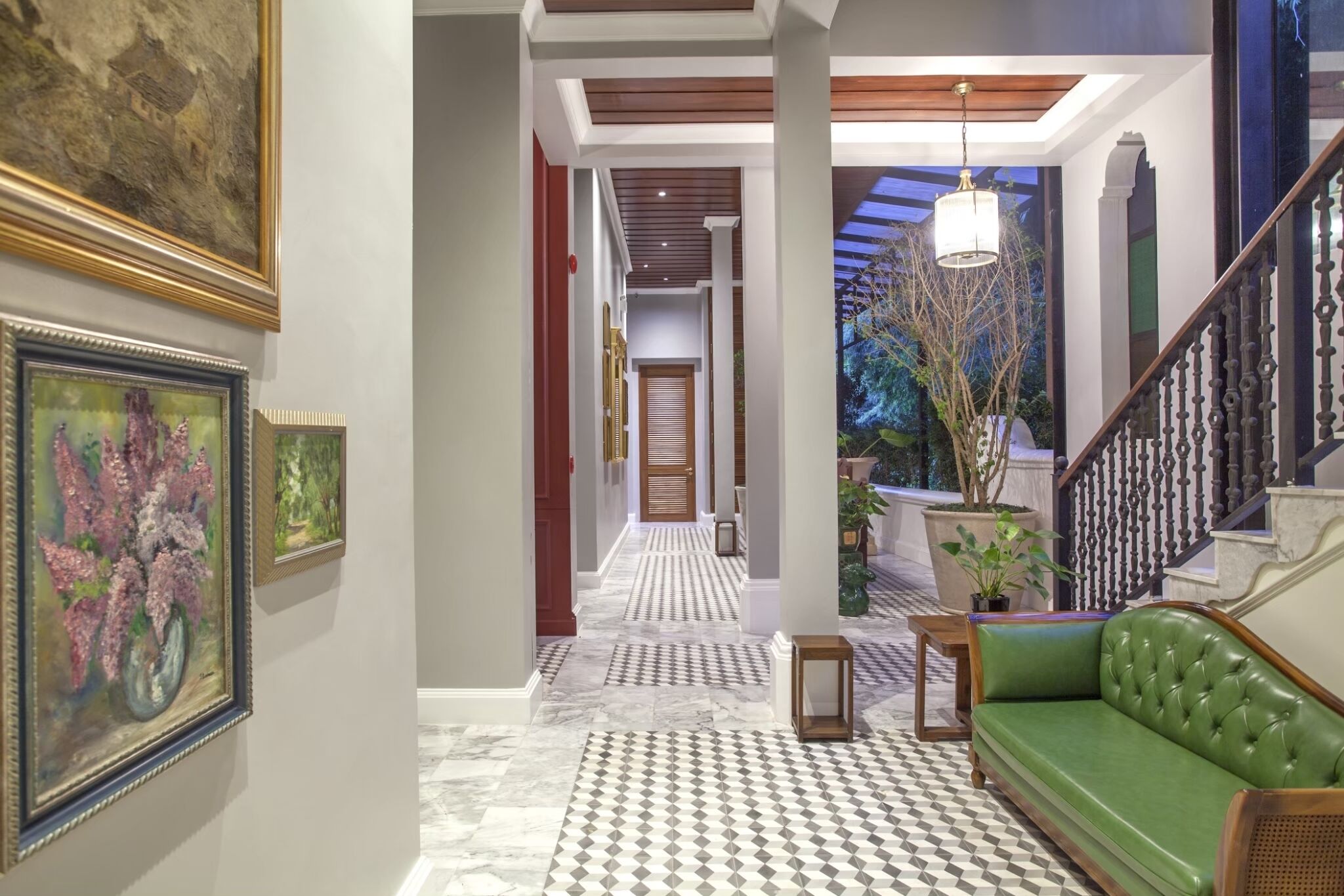 A hallway with a checkered floor, a green sofa, and framed artwork on the walls.