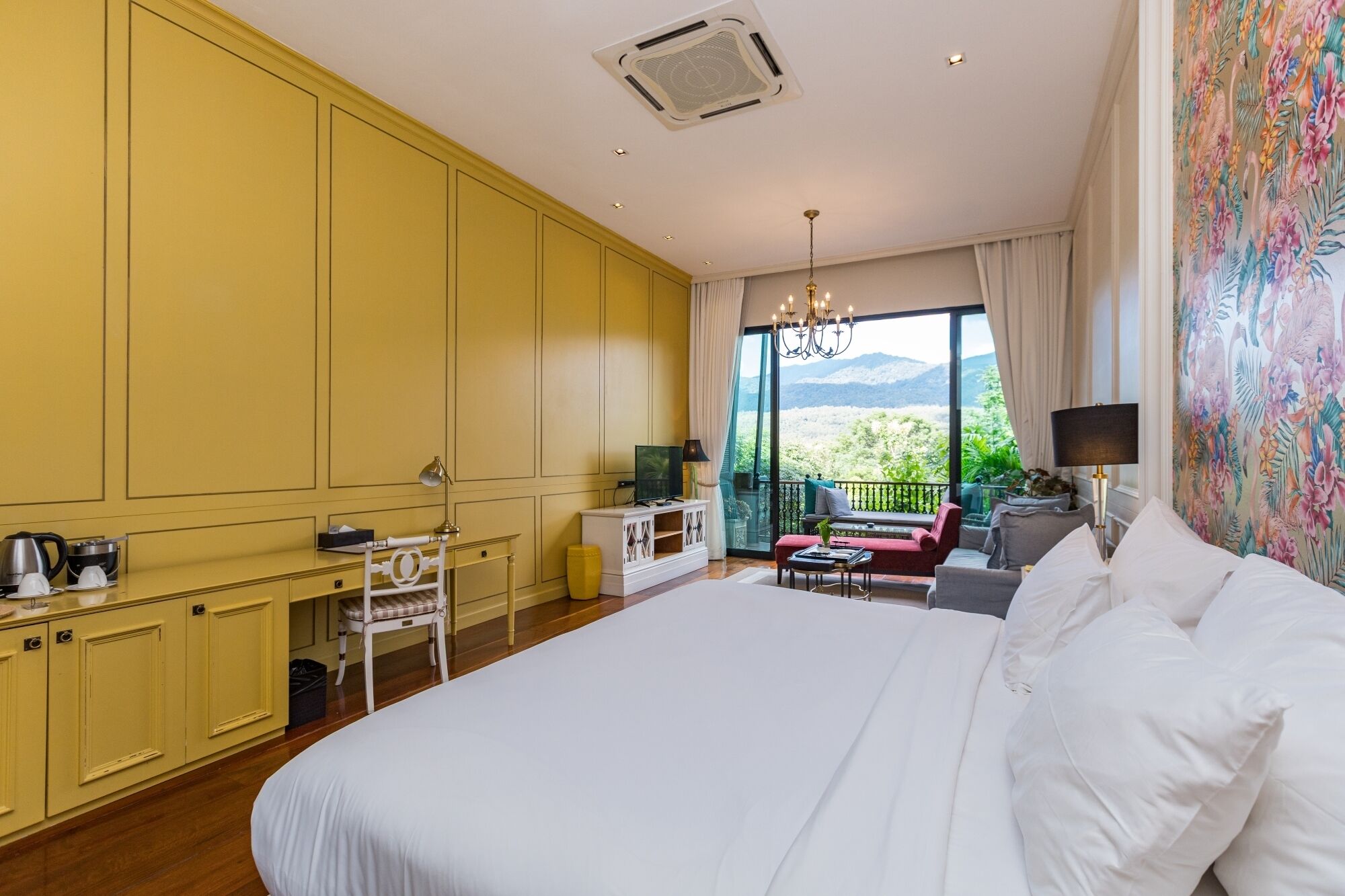 Una camera da letto con un letto grande, una scrivania, una sedia, un divano e vista sull'esterno.