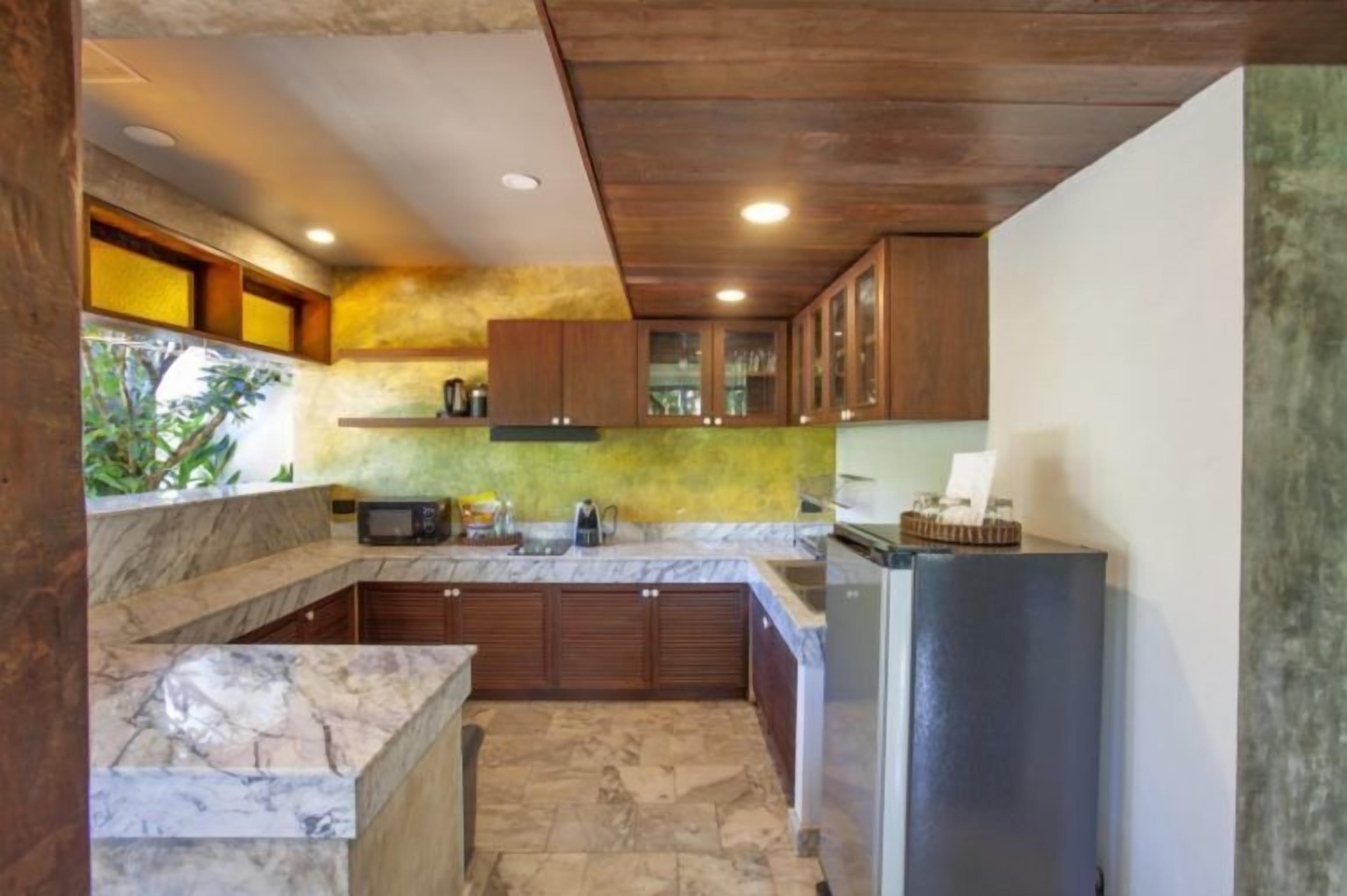 A compact kitchen with marble countertops, wooden cabinets, and a built-in microwave.
