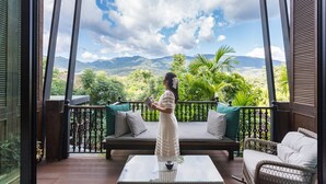 A balcony with a view of mountains, a sofa, and a table. - Chantra Khiri Chalet Chiang Mai (Hang Dong)