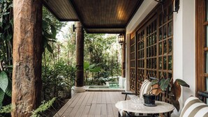 A wooden deck with a table and chairs, surrounded by lush greenery and a view of a garden. - Chantra Khiri Chalet Chiang Mai (Hang Dong)