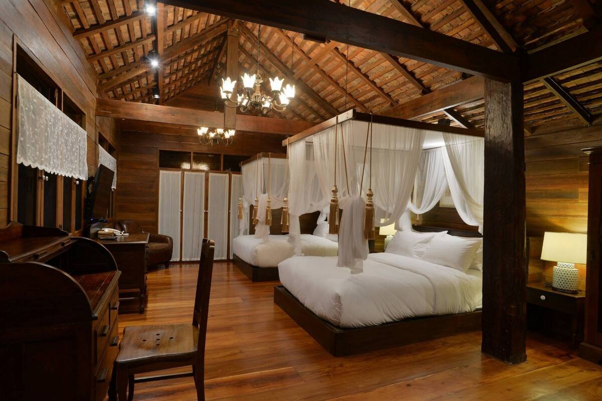 A room with a wooden ceiling and four beds with white bedding.