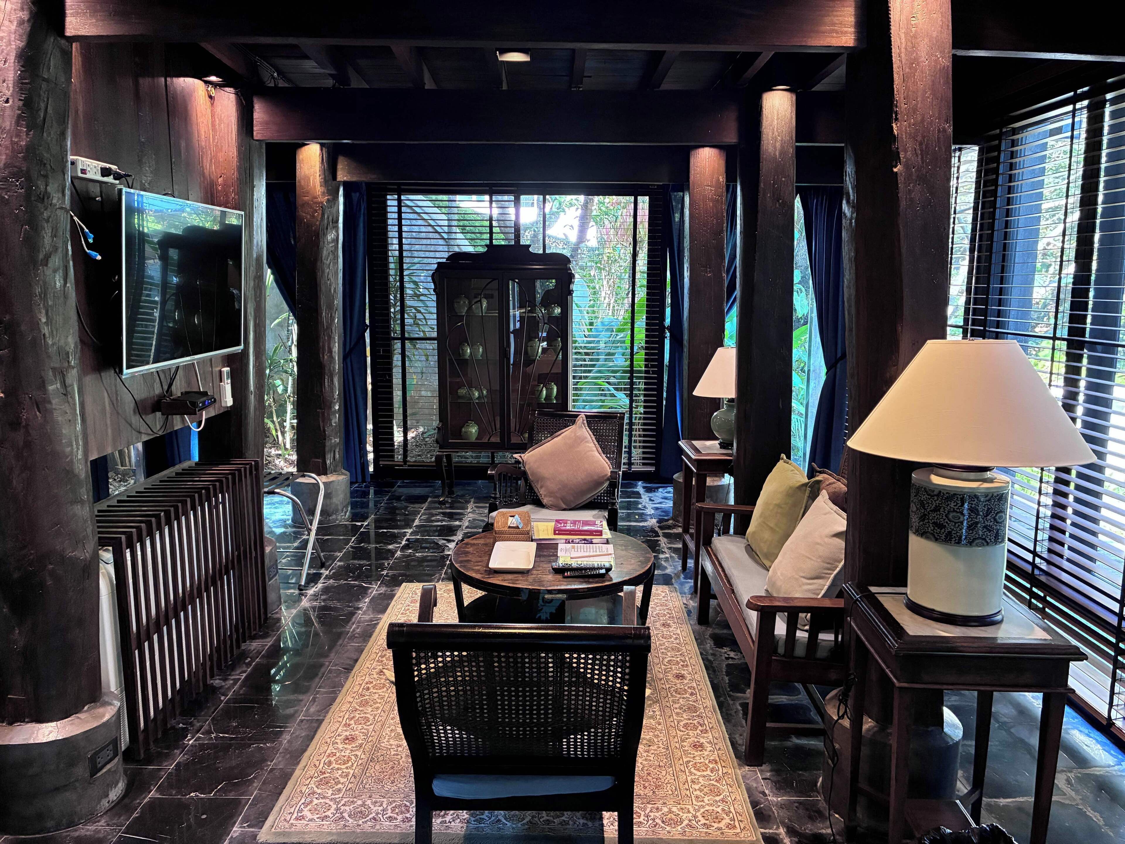 A spacious room with a large TV, a cabinet with decorative items, a sofa, a coffee table, and a lamp.