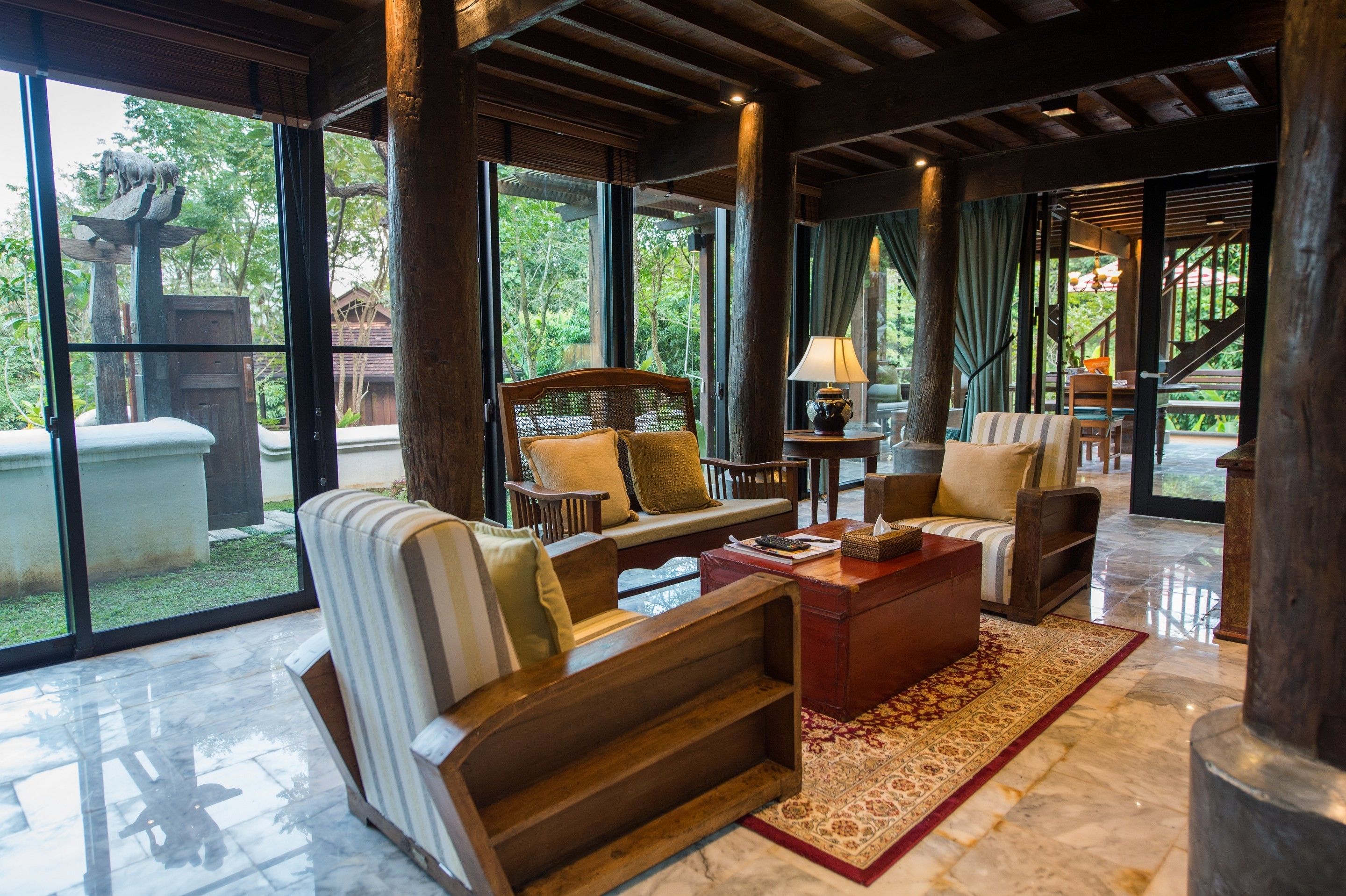 A spacious room with a large window, a sofa, a coffee table, and a lamp.
