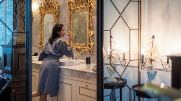 A bathroom with ornate gold mirrors, a marble sink, and a chandelier.