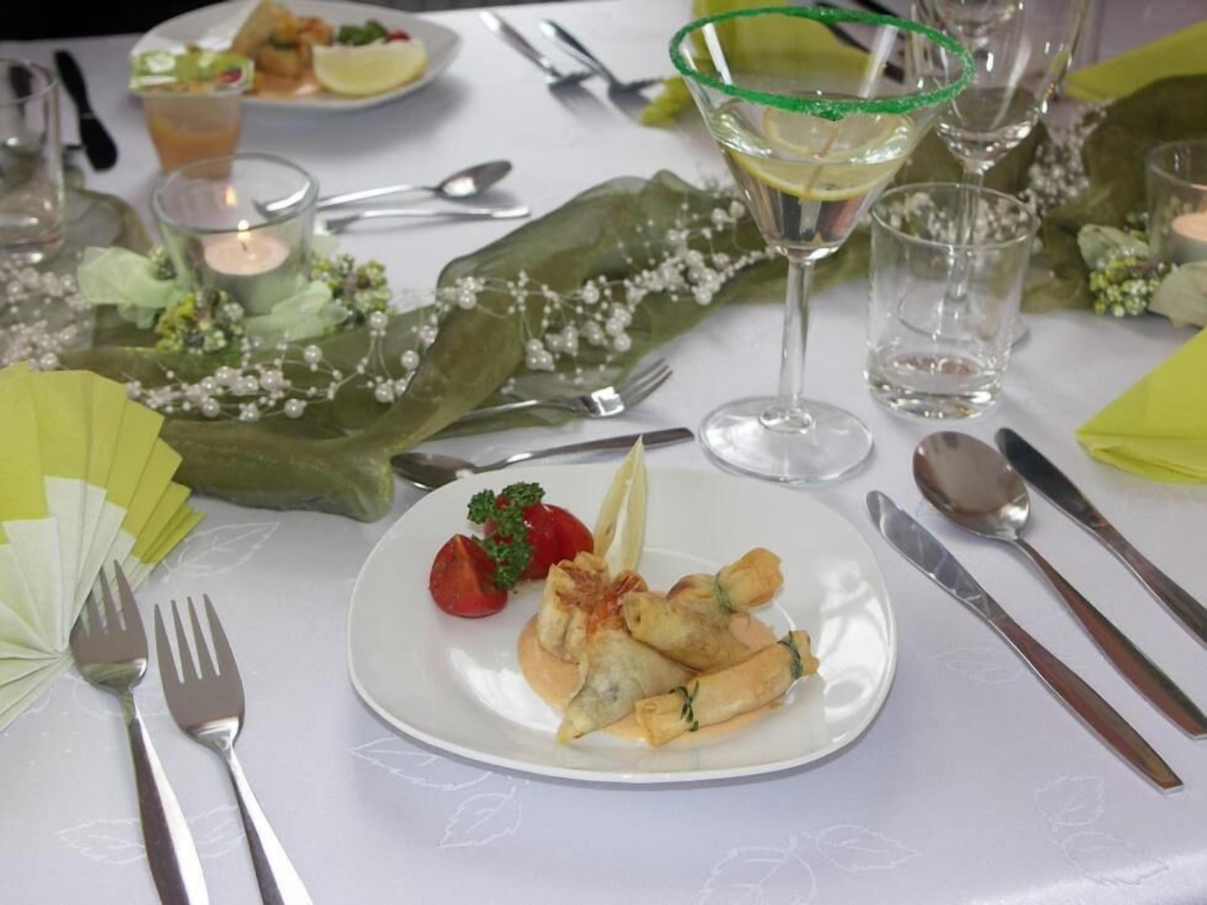 Una mesa dispuesta con una bandeja de aperitivos, una copa de martini y una vela.