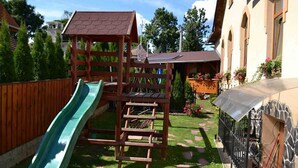 Estructura de juego de madera con tobogán y zona de escalada en un patio trasero.