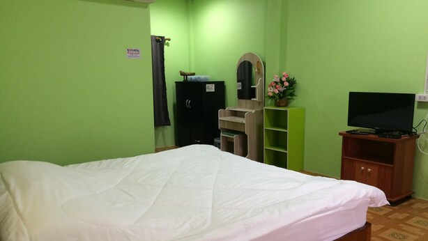 A bedroom with a bed, a wardrobe, a mirror, a television, and a small shelf with a plant. - Ban Khun Mor (Phrao)