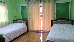 A room with two single beds, a wooden floor, and a window with curtains. - Ban Khun Mor (Phrao)